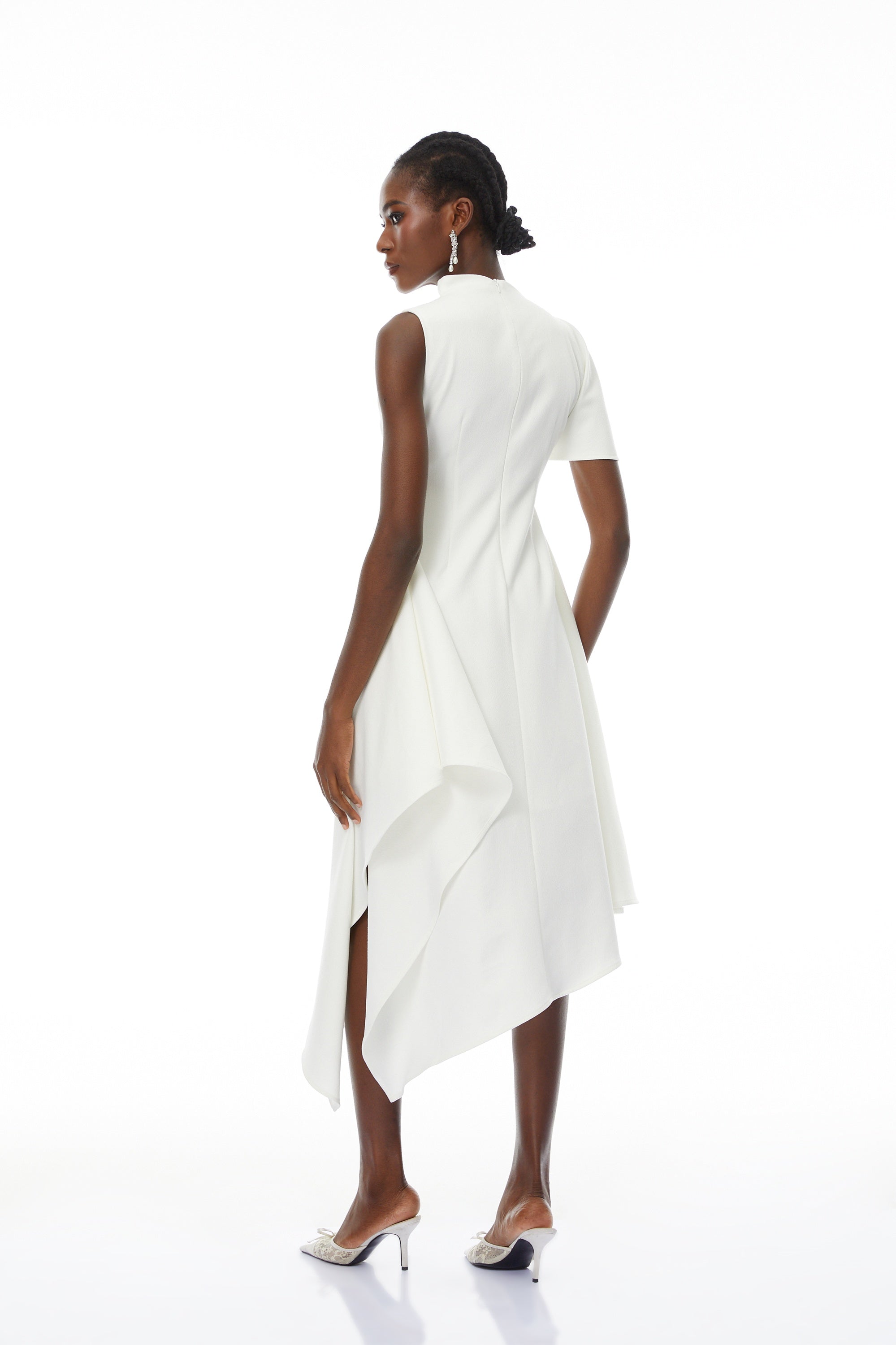 White sleeveless midi dress featuring a high drape neck with a brooch detail and a structured asymmetric handkerchief skirt