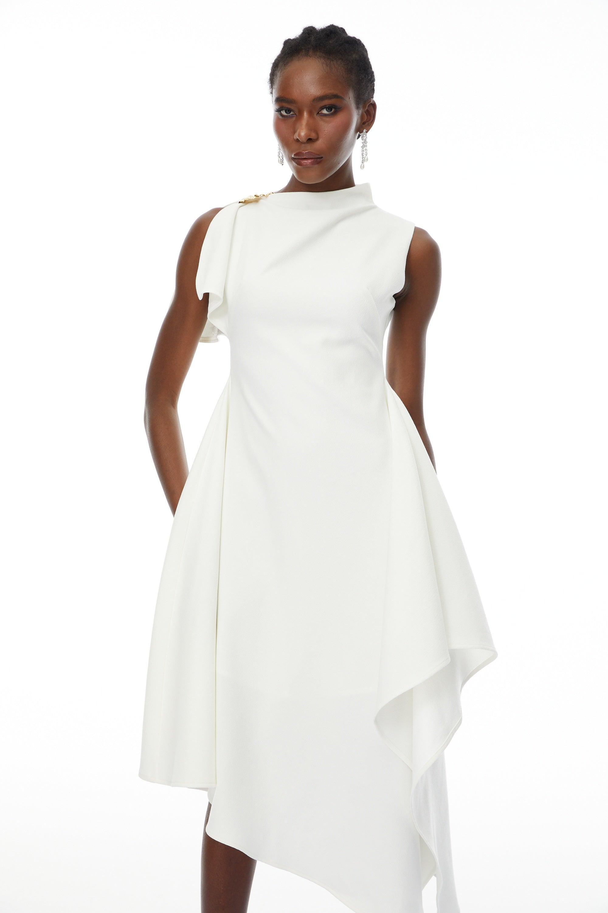 White sleeveless midi dress featuring a high drape neck with a brooch detail and a structured asymmetric handkerchief skirt