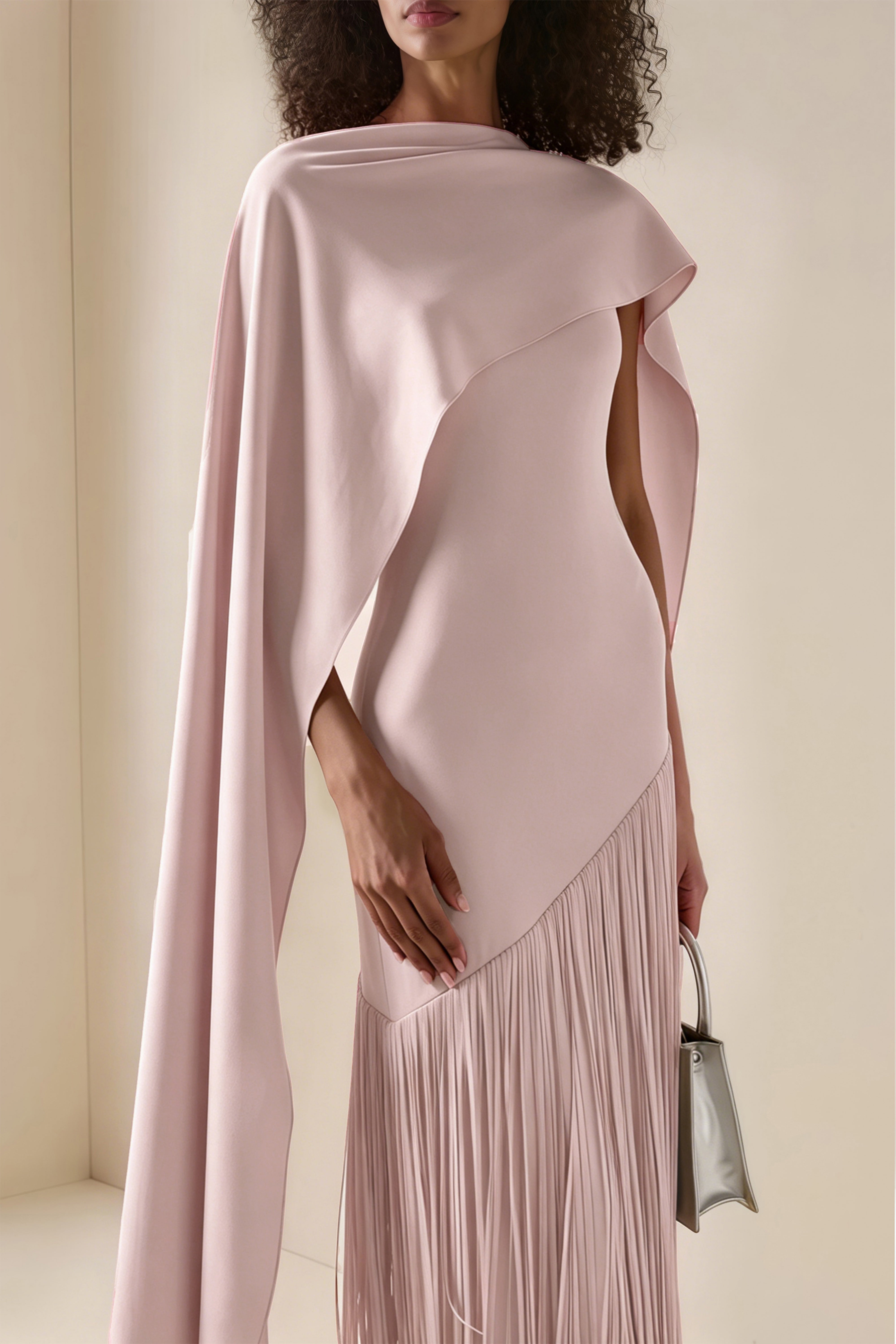 Light pink cape maxi dress with an asymmetrical waist and long fringe skirt