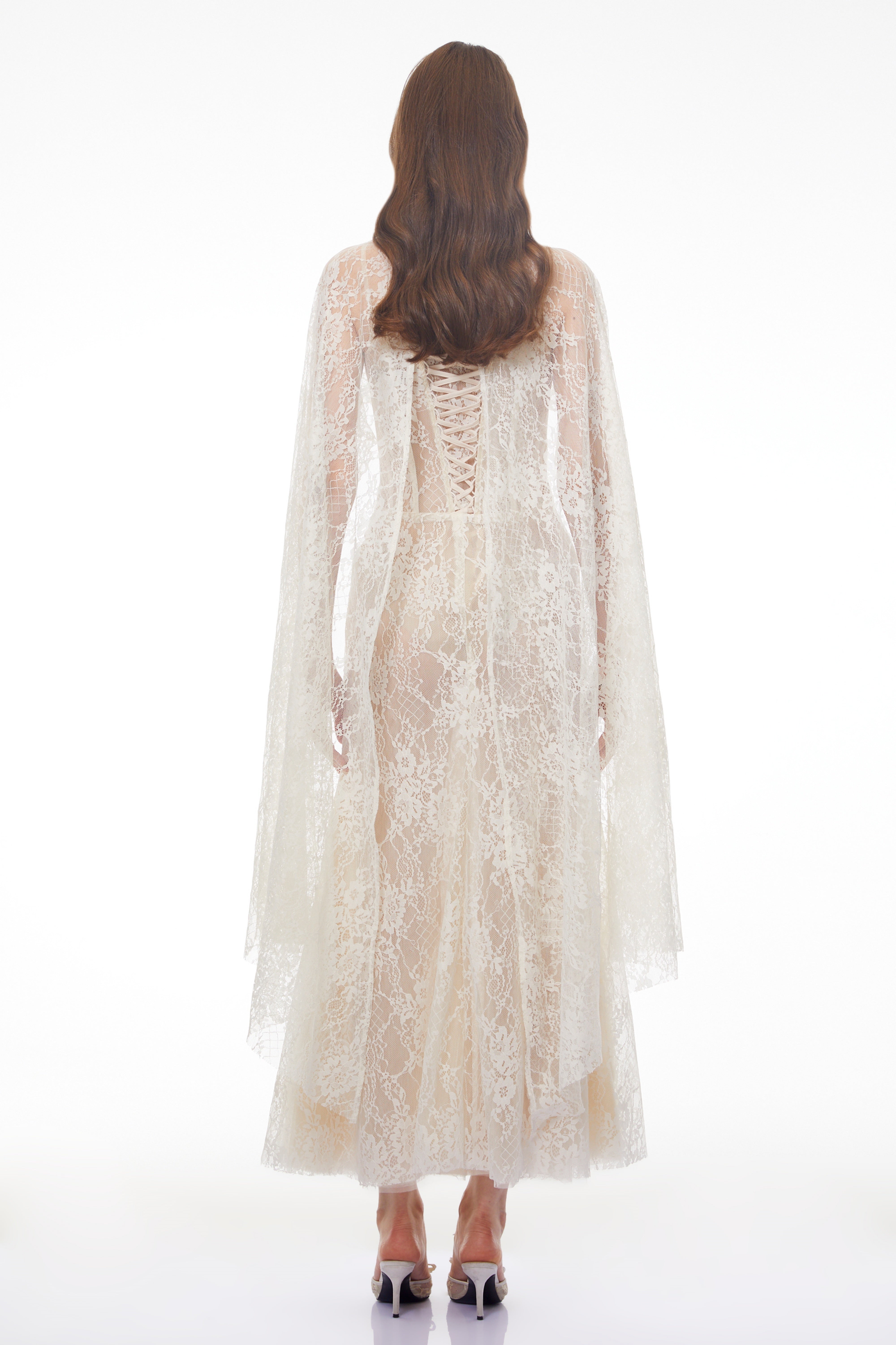 White lace maxi dress with a corset bodice, high neckline, and long draped cape sleeves