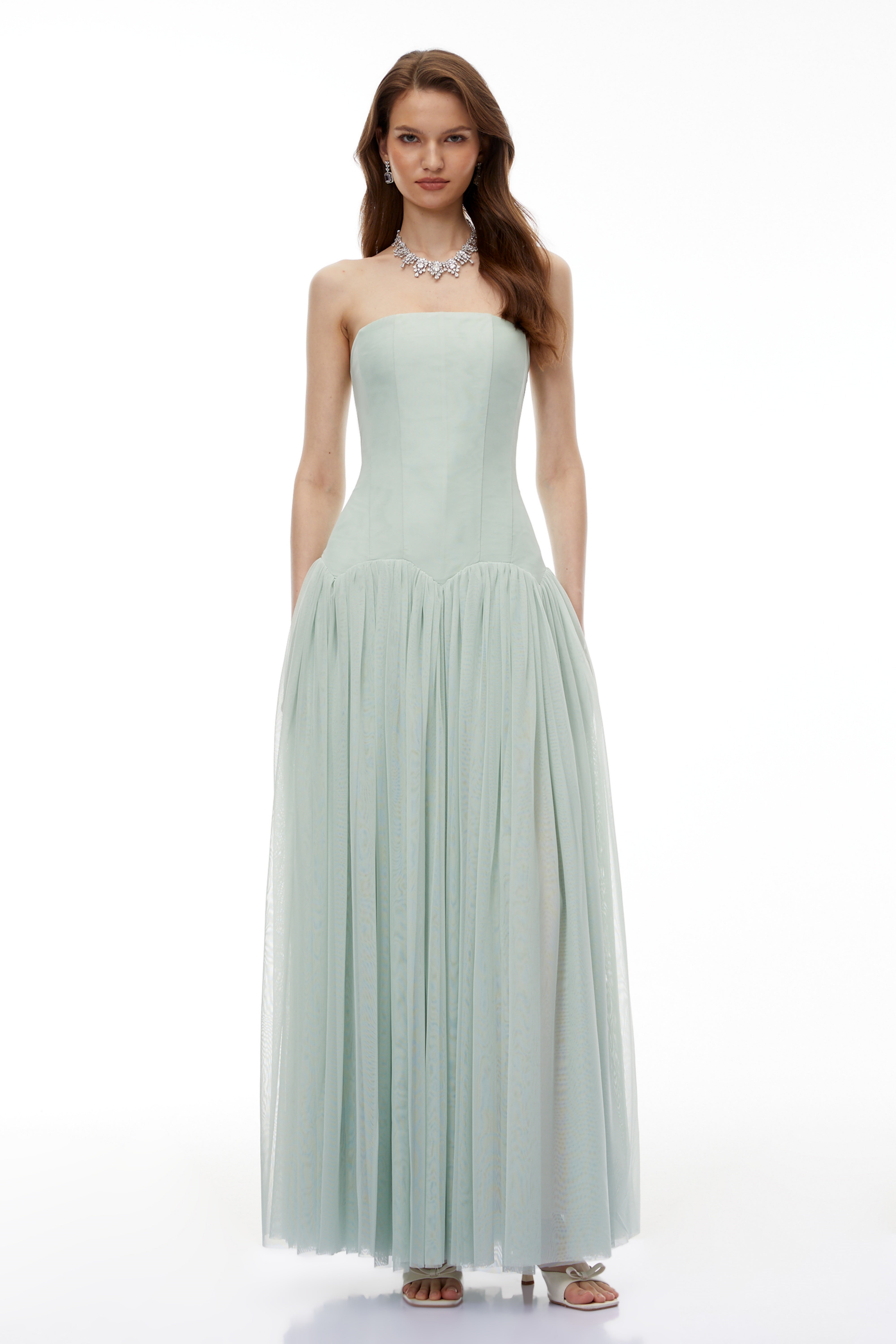 Sage green strapless gown with a corset-style bodice and flowing pleated skirt